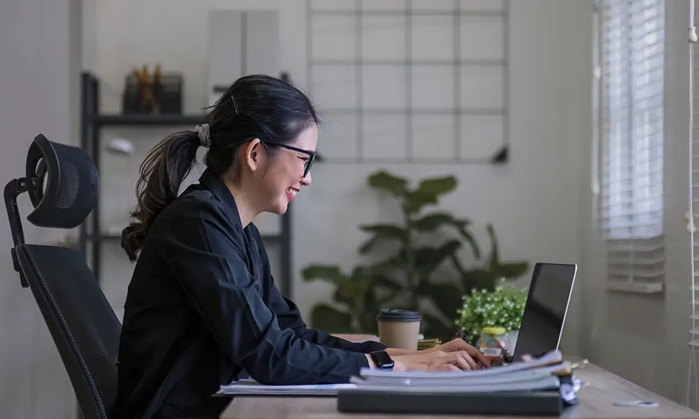 admin works at a laptop in the school office 
